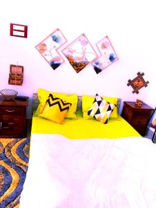 a bedroom with a yellow bed with pictures on the wall at JDreamland Homestay in Jorhāt