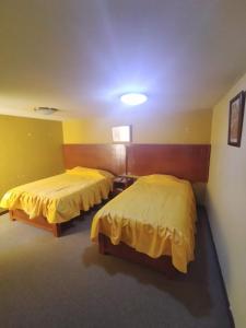 two beds in a room with yellow walls at TAWA INTI HOSTEL in Puno