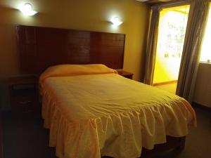 a bedroom with a bed with an orange comforter and a window at TAWA INTI HOSTEL in Puno