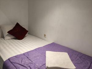 a small bedroom with a bed with a purple blanket at Ega S Hostel in Nusa Penida