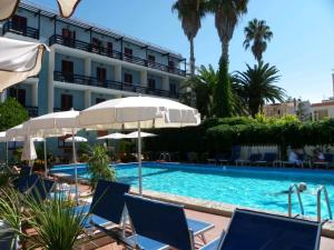 una piscina con sedie e ombrelloni accanto a un edificio di Hotel La Playa ad Alghero