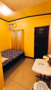 um quarto amarelo com uma cama e uma mesa em CheRi Backpackers Hostel em Moalboal