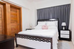 een slaapkamer met een bed met een roze kussen erop bij Torre Sky 01 - Apto. J9 in Santo Domingo