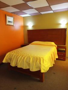 a bedroom with a bed with a yellow bedspread at TAWA INTI HOSTEL in Puno