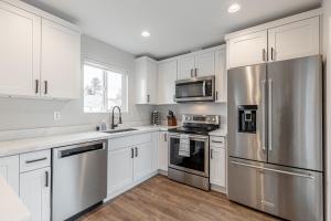 uma cozinha com armários brancos e electrodomésticos de aço inoxidável em Beautifully remodeled Rambler in South Seattle em Seattle