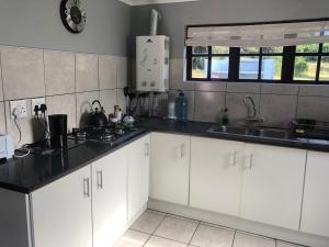 una cocina con armarios blancos y fregadero en Faithlands Self-Catering Cottages, en Port Elizabeth