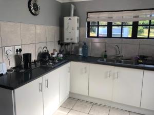 a kitchen with white cabinets and a sink at Faithlands Self-Catering Cottages in Port Elizabeth +13 photos