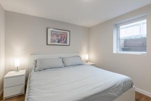 a white bedroom with a bed and two night stands at Beautifully remodeled Rambler in South Seattle in Seattle