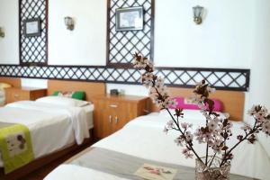 a hotel room with two beds and a vase with flowers at Gaisang Mêdog Aroma Fragrance Hotel in Lhasa