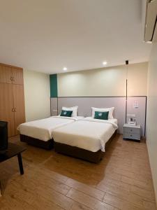 1 dormitorio con 2 camas con sábanas blancas y almohadas verdes en PENTAFIELD CITY RESIDENCE, en Amphoe Phra Khanong