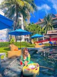 Eine Frau, die in einem Pool in einem Resort sitzt. in der Unterkunft River Beach Resort & Residences in Hoi An