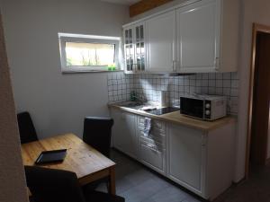 eine Küche mit weißen Schränken, einem Tisch und einer Mikrowelle in der Unterkunft Pension Rego in Pirna