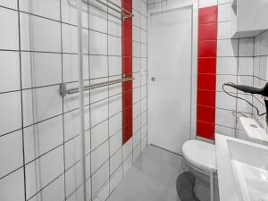 ein Bad mit einem WC und einer roten Wand in der Unterkunft Le Petit Torcieu in Torcieu