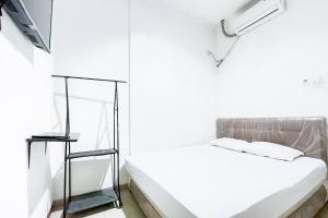 Citara Jaya Guesthouse Mitra RedDoorz في بيكاسي: غرفة بيضاء مع سرير ومرآة