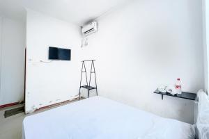 um quarto branco com uma cama e uma televisão em Citara Jaya Guesthouse Mitra RedDoorz em Bekasi