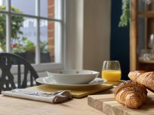 a table with a plate of bread and a glass of orange juice at Elegant, Luxury Family Apartment! Marlow Town Centre, Walk to Pubs in Buckinghamshire