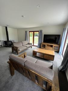 a living room with a couch and a flat screen tv at Sherwood Ranch Cottages - 405 Woodbank Road in Hanmer Springs