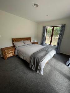a bedroom with a large bed and a window at Sherwood Ranch Cottages - 405 Woodbank Road in Hanmer Springs