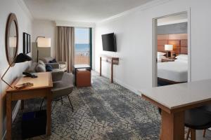 Habitación de hotel con cama, escritorio y espejo. en Sheraton Oceanfront Hotel, en Virginia Beach