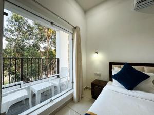 a bedroom with a balcony with a bed and a window at Golden Mango By Food Bunglow in Rāmnagar