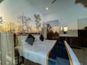 a bedroom with a bed and a large window at Golden Mango By Food Bunglow in Rāmnagar