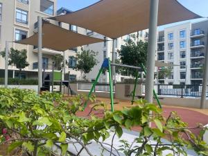 a playground with an umbrella in front of a building at Indigo beach residence 110 in Sharjah