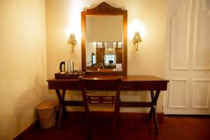 Habitación con escritorio con espejo y silla. en Sigiriya Village en Sigiriya