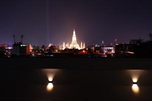 una vista de la ciudad por la noche con un templo iluminado en Baan Suandao Wat Arun, en Bangkok