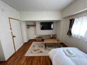 een kamer met een bed, een tafel en een tv bij Guest House Renga in Henza