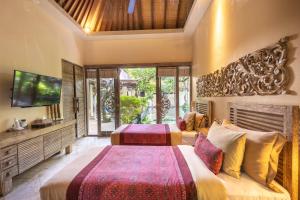 two beds in a room with a tv and a television at The Royal Purnama - Adults Only in Keramas