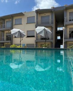 una piscina frente a un edificio con sombrillas en Appartement vue sur Mer Sidi Bouzid, en Moulay Abdallah