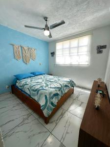 Un dormitorio con una cama con paredes azules y una ventana en Departamento Acapulco frente a la playa, en Acapulco