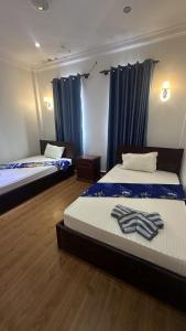 twee bedden in een kamer met blauwe gordijnen bij Aspire Homestay in Siem Reap