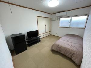 a bedroom with a bed and a flat screen tv at 松ノ木ハウス in Nobeji