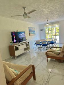 a living room with a television and a table with chairs at Departamento Acapulco frente a la playa in Acapulco