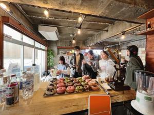 a group of people standing around a table with food at HOSTEL OE in Yoshinogawa