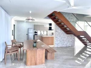 eine Küche und ein Esszimmer mit einem Tisch und einer Treppe in der Unterkunft Cozy Maison in Ban Bang Rathuk