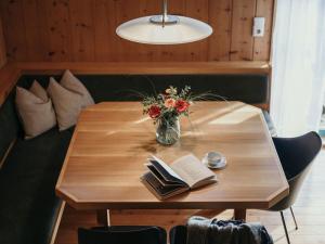 a wooden table with a vase of flowers and books at Bregenzerwald holiday home in Egg