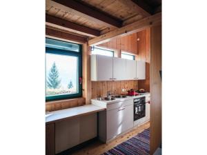 una cocina con armarios blancos y una ventana en Bregenzerwald holiday home en Egg