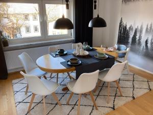 a dining room with a table and white chairs at Summit happiness at the purple beech in Bad Harzburg