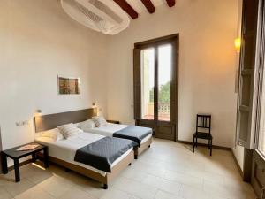 1 dormitorio con 2 camas y ventana en Castle apartment for two with private terrace, en La Torre de Claramunt