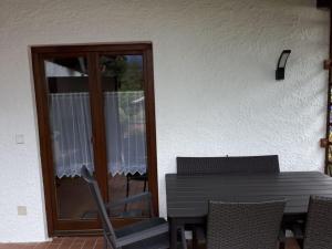 un patio con tavolo, sedie e porta in vetro di Holiday apartment Maurer Apartment Laber a Oberammergau