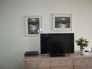 een televisie op een dressoir met twee foto's aan de muur bij Sea View 3 - Villa Bella Vista in Sassnitz