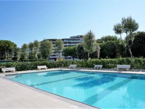 uma piscina com bancos e um edifício ao fundo em Nice apartment by the seabeach em Porto Santa Margherita di Caorle