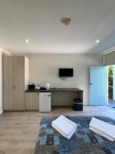 a living room with a kitchen and a tv on the wall at Time and Tide Hotel Motel in Collaroy