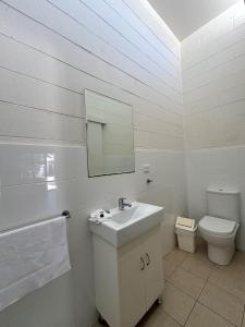 a white bathroom with a sink and a toilet at Time and Tide Hotel Motel in Collaroy