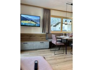 a living room with a table and a television on the wall at Apart Eder Modern retreat in Schwendau