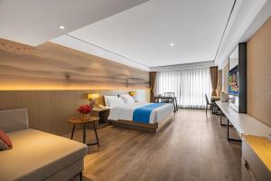 ein Hotelzimmer mit einem Bett und einer Couch in der Unterkunft Ramada Encore by Wyndham Kunming Guandu in Kunming + 46 Fotos