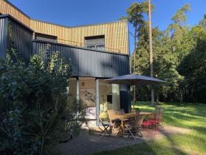 a house with a table and chairs and an umbrella at Super nice holiday home by the lake in Templin