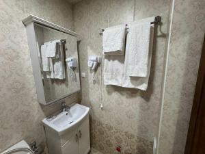a bathroom with a sink and a mirror and towels at Al-Khabib in Bukhara